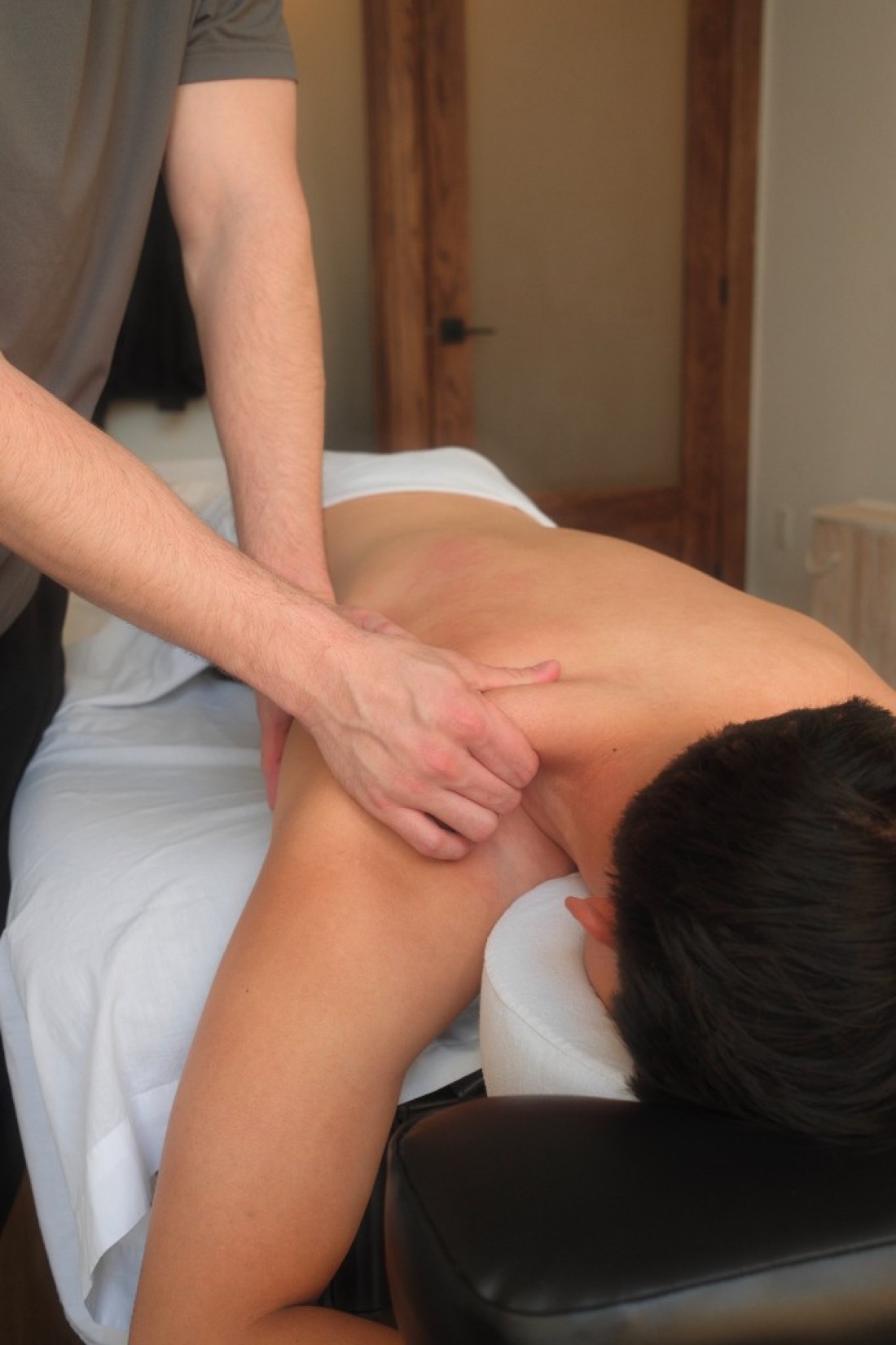 Registered massage therapist applying deep tissue work to a client’s shoulder